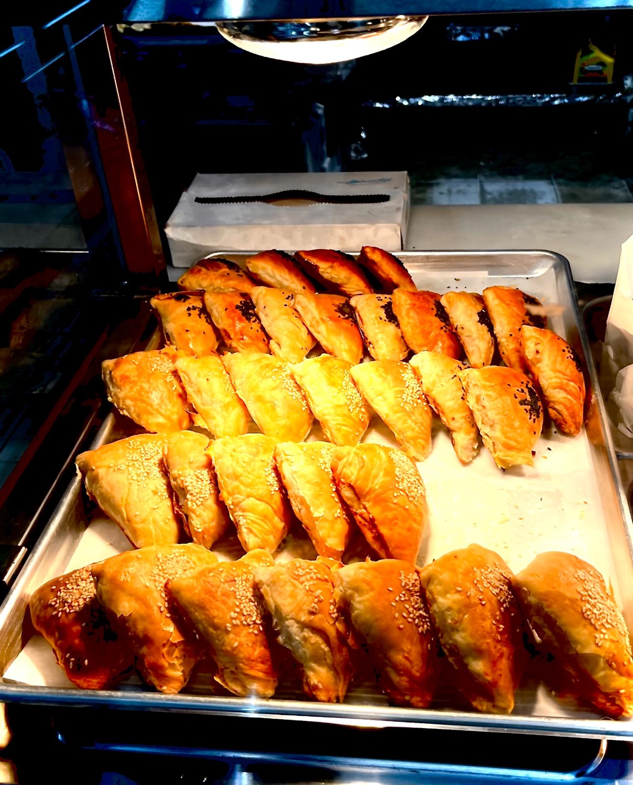 Trays of golden sambosa pastries with sesame and nigella seeds